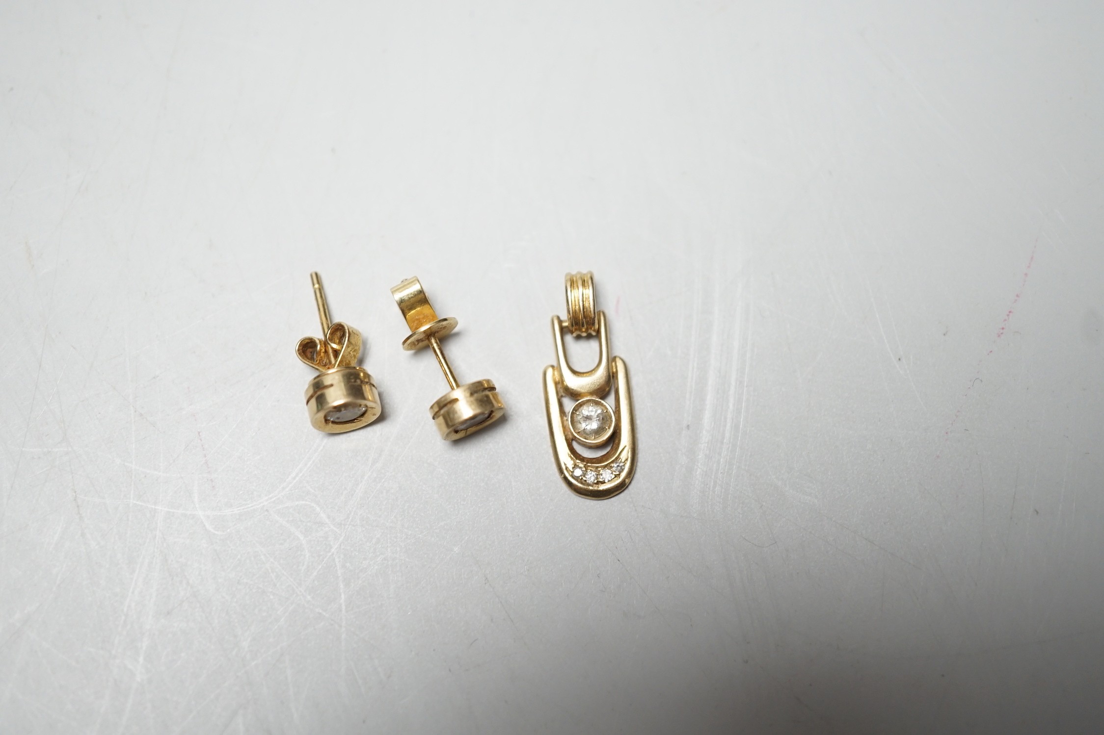 A modern pair of 585 yellow metal and solitaire diamond set ear studs, 6mm and a matching pendant, gross weight 3.9 grams.